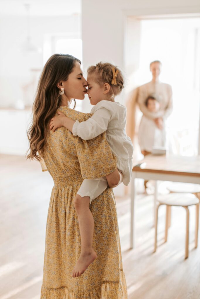 A loving embrace between a mother and her daughter in a sunlit room.